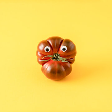 Fresh Tomato Primora With Googly Eyes Against Yellow Background.  Creative Food Layout. Funny  Vegetable Concept.