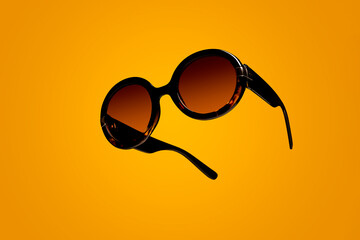 Black woman's female sunglasses floating on a summer inspired yellow background with copy space and...