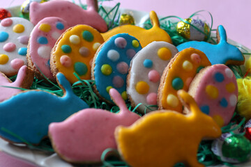 Homemade cookies in the shape of colorful eggs on a plate decorated for the Easter holiday