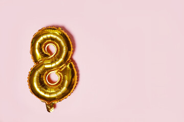 Golden number 8 eight made of inflatable balloon on pink background with copy space