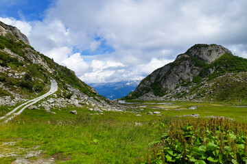 Grande prato verde all'interno di una vallata e bellissimo panorama delle montagne dal sentiero che...