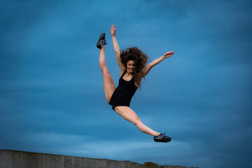 Fototapeta premium Super flexible woman jumping on the sky background. Concept of healthy lifestyle, happiness and joy