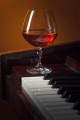 Snifter with brandy on a piano.