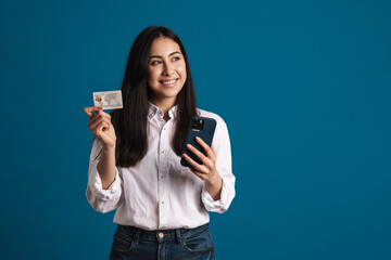 Happy beautiful asian girl posing with credit card and smartphone