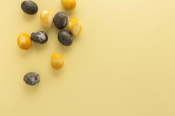 Golden and silver easter eggs scattered on yellow background, festive easter concept