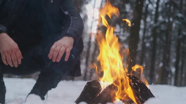 Man enjoys the fire at camping in the winter woods, making a fire, camping in snowy forest, man's winter activities, 4k UHD 60p Prores 422 HQ