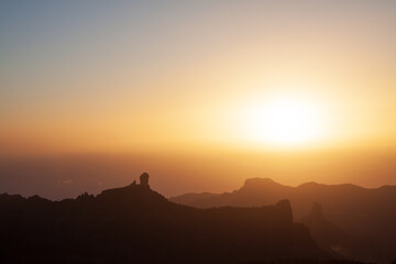 Silhouette of the iconic rock formation of Roque Nublo on the island of Gran Canaria seen at sunset in warm colors