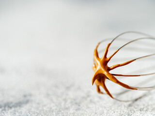 Whisk with trendy korean dalgona coffee. Whipped instant coffee on metal whisk over gray cement...