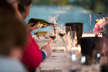 close up on a wine glasses, bottle and red wine being poured