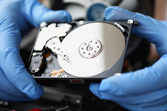 Gloved master holds computer hard drive. Computer equipment repair and maintenance concept