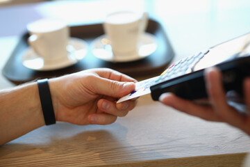 Male hand inserts plastic credit bank card into payment terminal. Pay by bank careers in public places concept