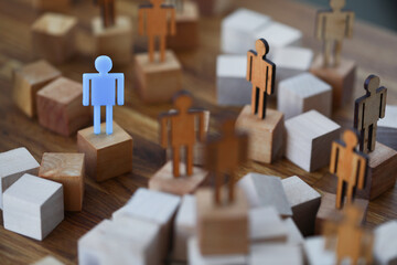 Wooden men on wooden cubes of brown color, one of them is blue. How to stand out among people and...