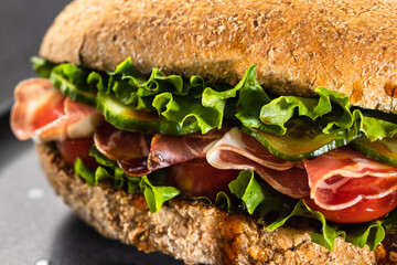 Fresh ham prosciutto sandwich with cream cheese and lettuce, tomato and cucumbers, macro view