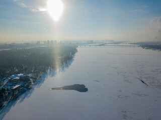 Light pillar from the sun over the Dnieper river in Kiev. Aerial drone view. Winter sunny morning.
