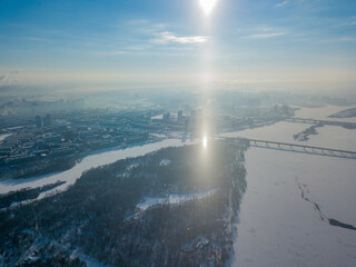 Light pillar from the sun over the Dnieper river in Kiev. Aerial drone view. Winter sunny morning.