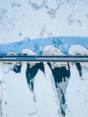 One metro train travels along the Kiev metro bridge. A shadow falls on the frozen Dnieper River. Aerial drone view. Winter sunny morning.