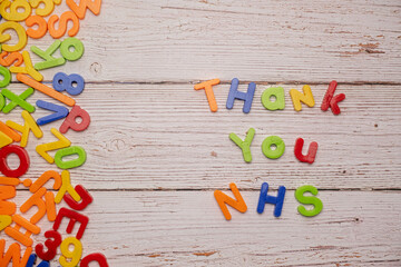 Colourful magnetic letters on a rustic white table during home school coronavirus spelling out Thank You NHS