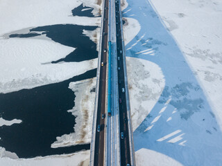 One metro train travels along the Kiev metro bridge. A shadow falls on the frozen Dnieper River. Aerial drone view. Winter sunny morning.