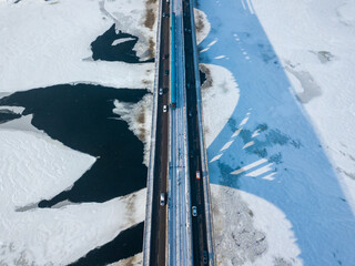 One metro train travels along the Kiev metro bridge. A shadow falls on the frozen Dnieper River. Aerial drone view. Winter sunny morning.