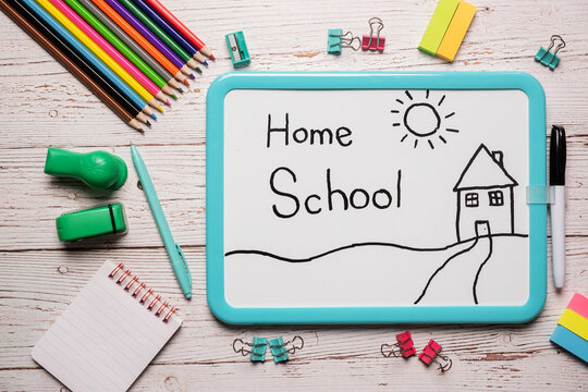 School supplies for homeschool laid out on a white wooden table with a white board with the words Home School written on it