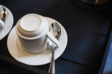 empty coffee cup upside down with spoon on dark tray with napkins in restaurant