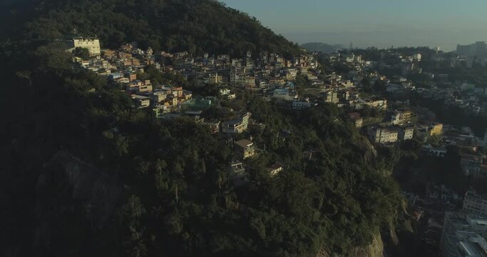 Rio de Janeiro mountain-top favela aerial at sunrise panning towards Tavares Bastos surrounded by forest
