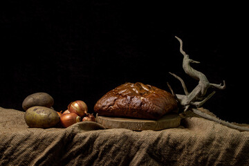 Black bread and vegetables on a black background. Borodino bread. Homemade baking. Bakery product....