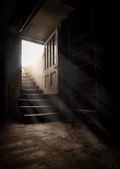 Foto op Plexiglas Oude deur Dark and creepy wooden cellar door open at bottom of old stone stairs bright sun light rays shining through on floor making shadows and scary sinister abandoned basement room underground