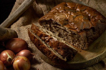 Black bread and vegetables on a black background. Borodino bread. Homemade baking. Bakery product. Peasant food