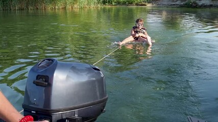 Funny teenage girl is sitting in scuba mask, life jacket on swimming circle in sea and holding on to rope. Dad rides his daughter in tow on water by tying an inflatable circle to motor boat. Vacation