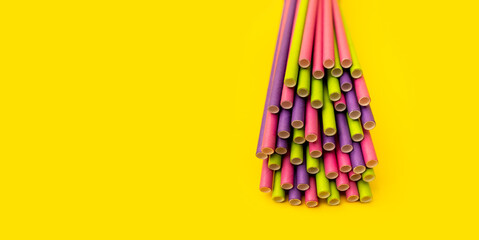 Paper straws of different colors on abright yellow background. Creative modern layout