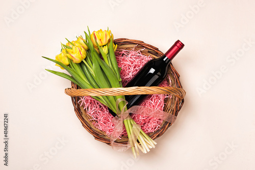 Bottle of red wine and tulip flowers in gift basket for Women's day and month, Mother's Day, birthday