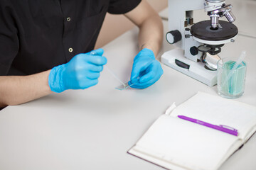 Scientist is using auto-pipette dropping a sample on the glass slide for microscope in medical laboratory. Close-up. Concept medicine, biology, research.