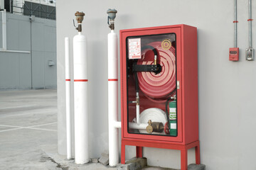 Fire Safety Concept, Fire extinguisher and fire hose reel in public building corridor. Locked Red Emergency Cabinet with Fire Extinguisher and Rolled Pipe.