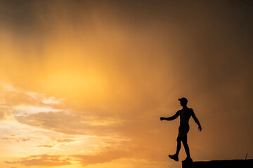 Silhouette of Man stepping from the edge during dramatic sunset. Concept goal, step forward and risk