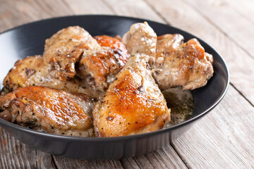 Baked chicken in a bowl on wooden table, homemade food