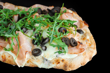 Pinsa romana gourmet italian cuisine on black background. Scrocchiarella traditional dish. Food delivery from pizzeria. Pinsa with meat, arugula, olives, cheese.