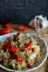 Groats with eggplant and cherry tomatoes on a rustic plate
