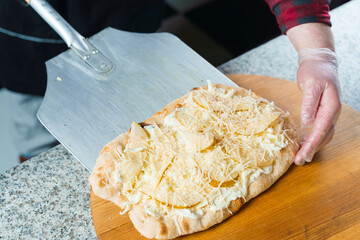 Chef cooking pinsa romana with pear, cheese, prosciutto in delivery box. Scrocchiarella gourmet...