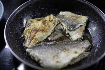 Delicious roast dorado or sea bream fish with lemon and orange slices, spices, and rosemary on baking sheets on wooden table