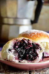 Sweet buns with blueberries on a pink plate on a wooden background