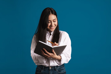 Happy beautiful asian girl writing down notes in planner