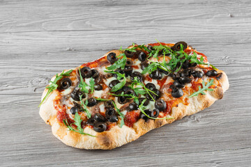 Pinsa romana gourmet italian cuisine on grey wooden background. Scrocchiarella traditional dish....