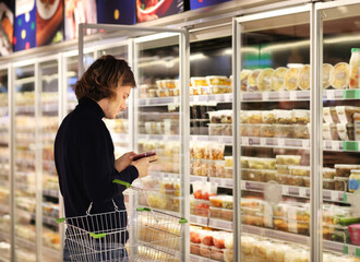 young man shopping in supermarket, reading product information.