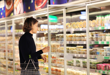 young man shopping in supermarket, reading product information.