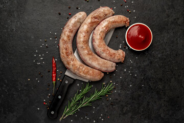 grilled sausages with spices on a knife on a stone background
