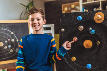 Happy school boy making a solar system for a school science project at home