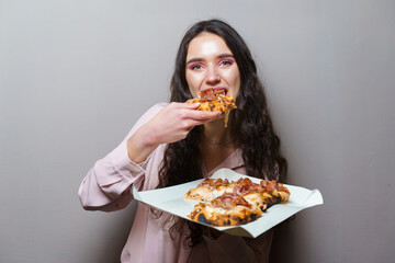Girl courier eating pinsa pizza romana gourmet italian cuisine on grey background. Holding...