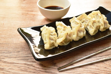 steamed Gyoza or Japanese dumpling stuffed minced pork dipping shoyu sauce on plate