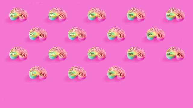 Toy plastic rainbow on a pastel pink background. A colored spiral for play and stunts, popular in the 90s. 